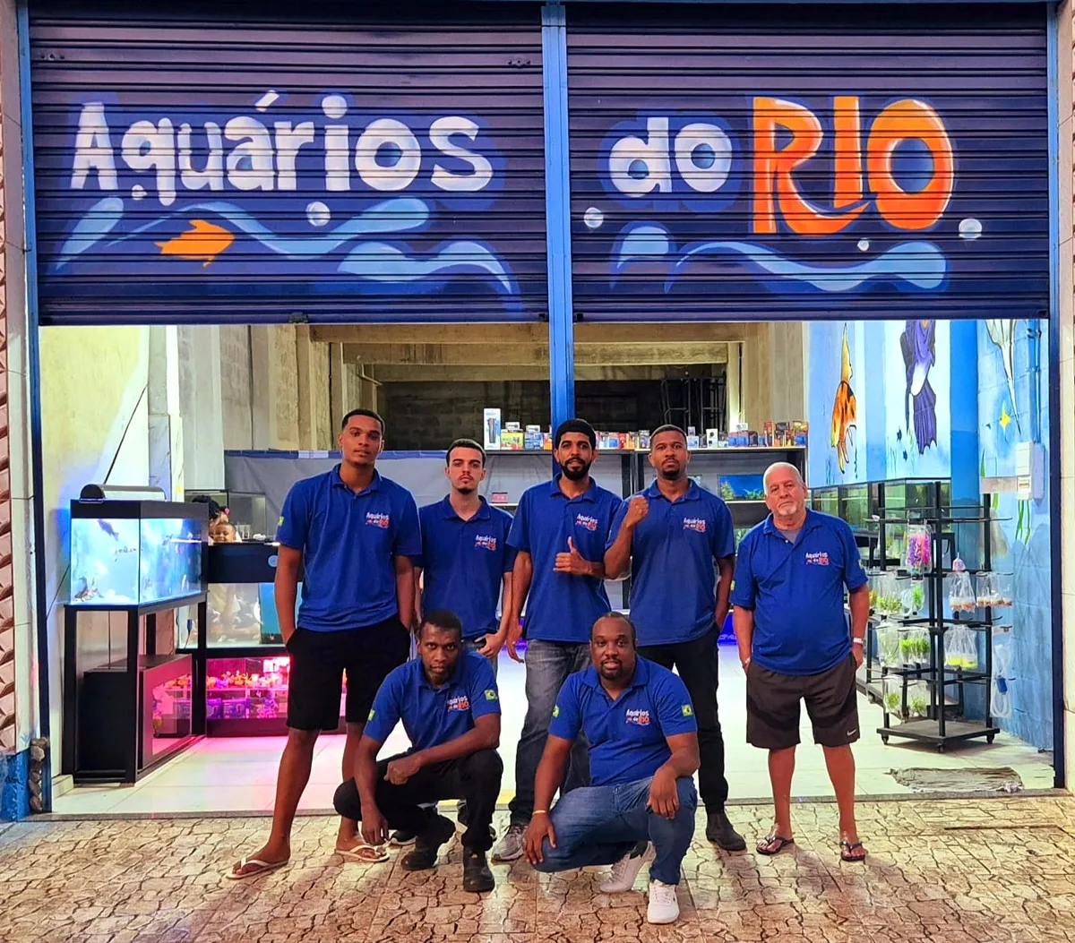 A equipe da Aquários do Rio, de uniforme azul, na porta da loja em Vigário Geral
